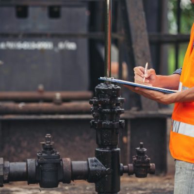 workers-standing-checking-beside-working-oil-pumps-min